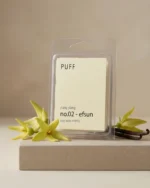 PUFF No.02 Efsun ylang ylang kokulu soya wax melts ürünü, çiçek ve vanilya detayları eşliğinde minimalist arka planda sergilenmiş.
