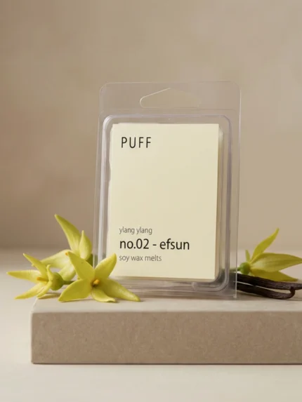 PUFF No.02 Efsun ylang ylang kokulu soya wax melts ürünü, çiçek ve vanilya detayları eşliğinde minimalist arka planda sergilenmiş.