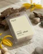 PUFF No.02 Efsun ylang ylang kokulu soya wax melts ürünü, çiçek ve vanilya detayları eşliğinde minimalist arka planda sergilenmiş.