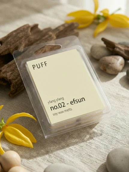 PUFF No.02 Efsun ylang ylang kokulu soya wax melts ürünü, çiçek ve vanilya detayları eşliğinde minimalist arka planda sergilenmiş.