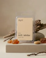 PUFF No.03 Kehribar amber kokulu soya wax melts ürünü, doğal taş ve reçine detayları eşliğinde minimalist arka planda sergilenmiş.